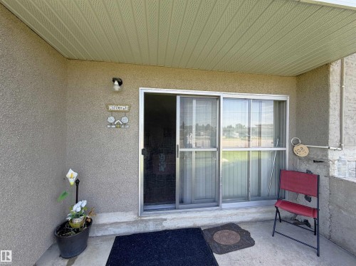 Covered patio area featuring a sliding glass door with screen, stucco exterior, and a soffit ceiling - #108 4501 51 St, Leduc, AB - Outdoor With Exterior