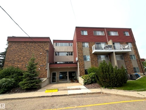 Multi-story building featuring a brick and stucco exterior, red shingle roofing, and multiple balconies with white railings - #108 4501 51 St, Leduc, AB - Outdoor