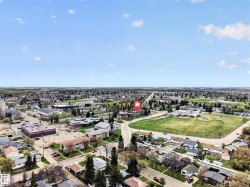 Aerial perspective showcasing a developed neighborhood with residential properties, commercial buildings, and open green spaces under a clear sky - 