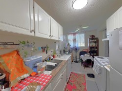Kitchen featuring white upper and lower cabinetry, a stainless steel sink, a built-in range, and a ceiling fan - 