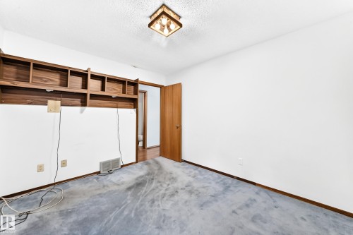 Room featuring wood-finish built-in shelving, white walls, and a ceiling-mounted light fixture - 4208 Ramsay Road Nw, Edmonton, AB - Indoor Photo Showing Other Room