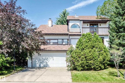 Multi-level residence featuring a two-car garage, upper-level balcony with wood railing, and an arched window - 4208 Ramsay Road Nw, Edmonton, AB - Outdoor
