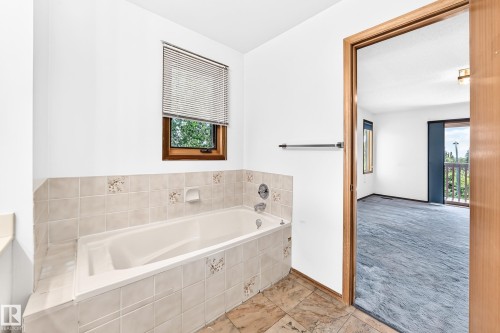 Soaking tub with tiled surround and integrated window - 4208 Ramsay Road Nw, Edmonton, AB - Indoor Photo Showing Bathroom