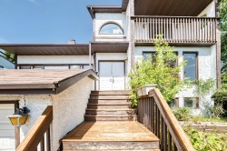 Multi-level exterior featuring white stucco siding and dark trim - 