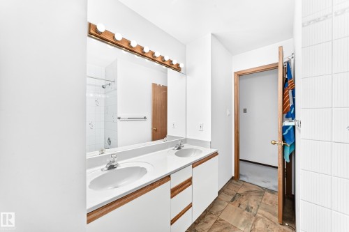 Dual vanity with white cabinetry, wood-finish trim, and white countertops - 4208 Ramsay Road Nw, Edmonton, AB - Indoor Photo Showing Bathroom