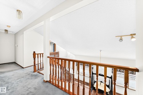 Upper-level landing featuring hardwood banister and spindles, track lighting, and a high ceiling - 4208 Ramsay Road Nw, Edmonton, AB - Indoor Photo Showing Other Room