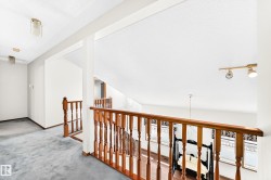 Upper-level landing featuring hardwood banister and spindles, track lighting, and a high ceiling - 
