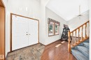 Entryway featuring double panel doors with brass hardware, slate tile flooring, wood-finish flooring, a wood staircase with carpeted treads, and vaulted ceilings - 4208 Ramsay Road Nw, Edmonton, AB  - Indoor Photo Showing Other Room 