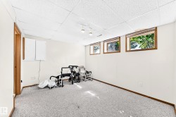 Spacious room featuring light-colored carpeting, white walls, and a dropped ceiling with integrated lighting - 