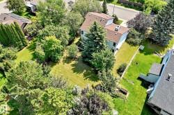 Expansive residential property featuring a large green lawn, mature trees, and established landscaping - 