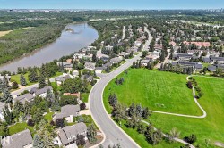 Aerial depiction of a residential area featuring a river, mature trees, and a large green space - 
