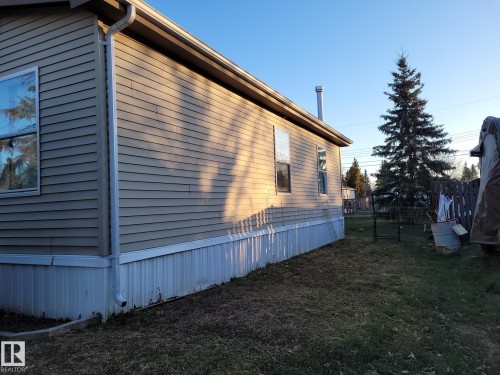 Exterior featuring tan horizontal siding, white trim, and a white gutter system - 5273 50 Street, Mayerthorpe, AB - Outdoor