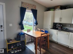 Kitchen area featuring white cabinetry, dark countertops, and wood-finish flooring - 