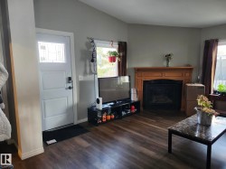Living area featuring wood-finish flooring and a fireplace with a wood mantle and black insert - 