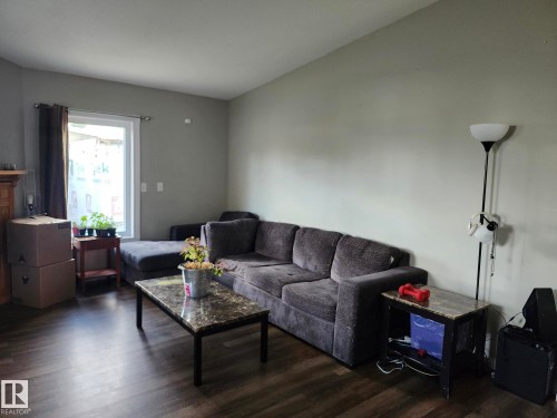 Spacious living area featuring wood-finish flooring, light gray walls, a white-framed window, and a recessed ceiling - 5273 50 Street, Mayerthorpe, AB - Indoor Photo Showing Living Room