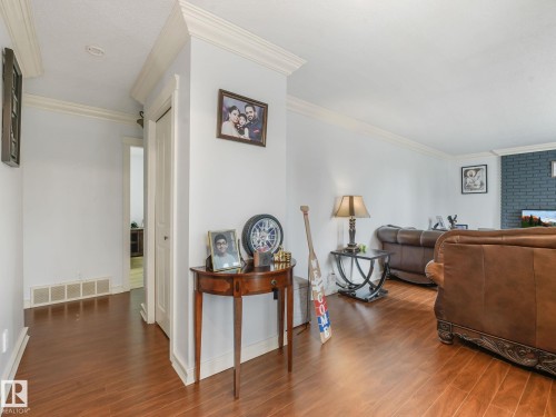 Room featuring wood-finish flooring, white wall paint, and crown molding - 10912 5 Avenue Sw, Edmonton, AB - Indoor