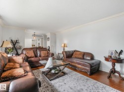 Light-filled living area featuring wood-finish flooring, crown molding, and recessed lighting - 