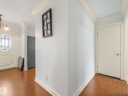 Foyer showcasing wood-finish flooring, white baseboards, and crown molding - 