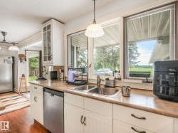 Kitchen featuring wood-finish flooring, white cabinetry, a double basin stainless steel sink, and stainless steel dishwasher - 