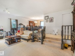 Carpeted living area featuring a multi-level design, white walls, and a window with exterior views - 