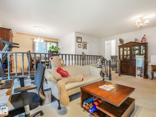 Carpeted living area with dark wood banister and balusters - 10912 5 Avenue Sw, Edmonton, AB - Indoor