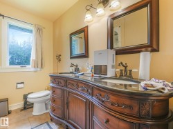 Double vanity with ornate wood cabinetry, dark countertop, and two mirrors with wood frames - 