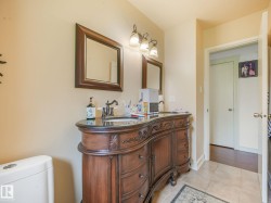 Double vanity with dark wood-finish cabinetry, dark countertops, and dual undermount sinks - 