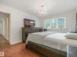 Bedroom featuring wood-finish flooring, a multi-pane window with blinds, and a crystal chandelier - 