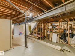 Unfinished basement space featuring exposed wood joists, structural framing, and concrete flooring - 