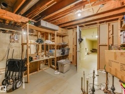 Unfinished basement space featuring exposed wood joists, concrete foundation walls, and painted concrete flooring - 