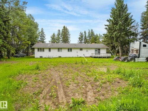Expansive rear yard space featuring a white single-story residence with a rear deck and mature perimeter trees - 10912 5 Avenue Sw, Edmonton, AB - Outdoor