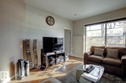 Living area with wood-finish flooring, light-toned walls, and a large window - 