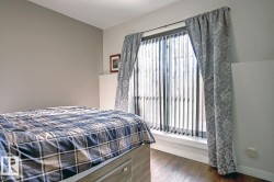 Room featuring wood-finish flooring, a large window with vertical blinds, and patterned drapes - 