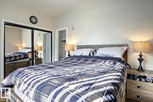 Bedroom featuring a wood-finish headboard, light-toned walls, and wood-finish flooring - 102 10905 109 Street, Edmonton, AB - Indoor Photo Showing Bedroom