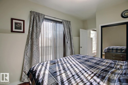 Sliding glass door with vertical blinds and drapery panels - 102 10905 109 Street, Edmonton, AB - Indoor Photo Showing Bedroom