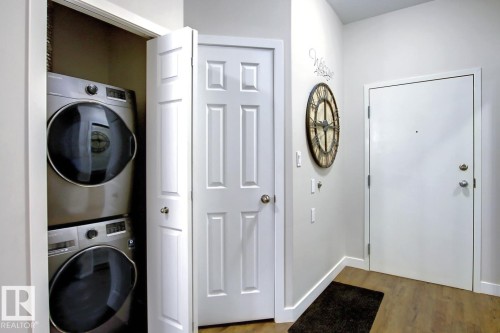 Entryway featuring wood-finish flooring and a white paneled door - 102 10905 109 Street, Edmonton, AB - Indoor Photo Showing Laundry Room