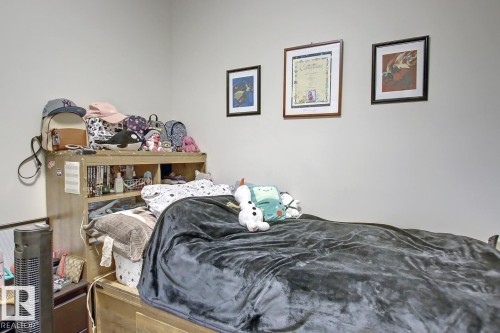 Bedroom featuring light-toned walls and wood-finish bed frame with an integrated headboard storage unit - 102 10905 109 Street, Edmonton, AB - Indoor Photo Showing Bedroom