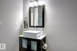 Bathroom vanity with a rectangular vessel sink, polished chrome faucet, dark wood-finish cabinetry, white countertop, and framed mirror - 