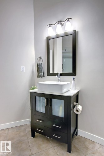 Dark wood vanity with a white vessel sink, complemented by a white countertop - 102 10905 109 Street, Edmonton, AB - Indoor Photo Showing Bathroom