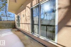 Outdoor patio featuring a concrete surface, stucco exterior, overhead soffit, and sliding glass door access - 