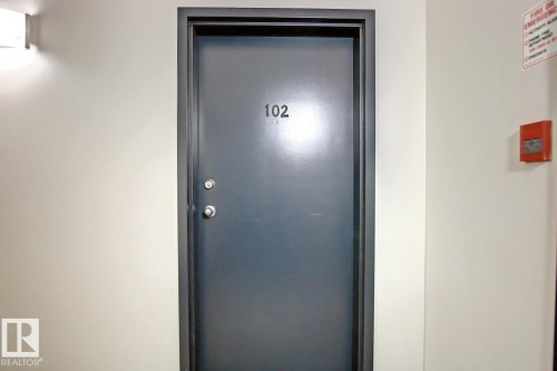 Solid core entry door with a dark finish and contrasting trim - 102 10905 109 Street, Edmonton, AB - Indoor Photo Showing Other Room