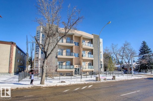 Contemporary multi-story building featuring stucco and stone-finish exterior, multiple private balconies with glass railings, and expansive window panels - 102 10905 109 Street, Edmonton, AB - Outdoor With Facade