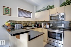Compact kitchen featuring a black countertop peninsula, stainless steel appliances, and cream-colored cabinetry - 