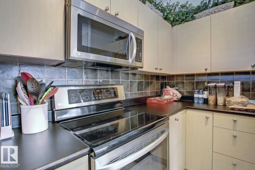 Modern kitchen featuring stainless steel appliances, including an over-the-range microwave and an electric range - 102 10905 109 Street, Edmonton, AB - Indoor Photo Showing Kitchen