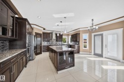 Gourmet kitchen featuring dark wood cabinetry, light-toned granite countertops, and a full tile backsplash - 