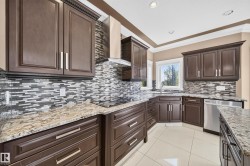 Kitchen featuring dark wood cabinetry, granite countertops, a mosaic tile backsplash, stainless steel appliances, and tile flooring - 
