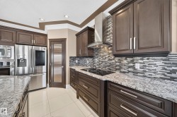 Gourmet kitchen featuring dark wood cabinetry, light granite countertops, stainless steel appliances, mosaic tile backsplash, and recessed lighting - 