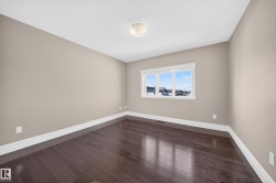 Interior room featuring dark wood-finish flooring, light neutral-toned walls, and white baseboards - 