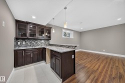 Built-in wet bar featuring dark wood-finish cabinetry, a tile backsplash, and granite countertops - 