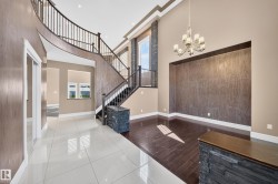 Grand entry featuring a curved staircase with dark wood railings, contrasting tile flooring, and recessed lighting - 